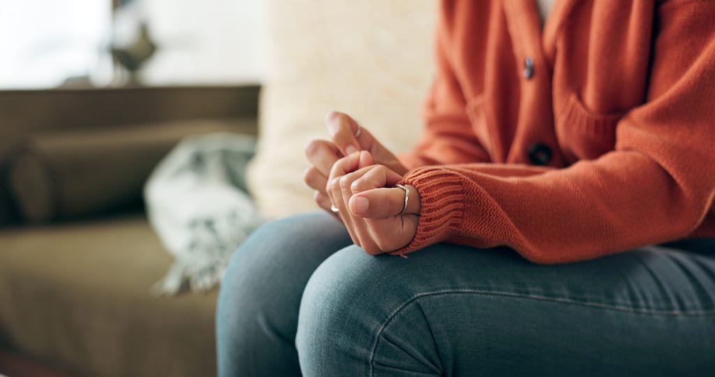Person with clasped hands representing the emotional weight of living with PTSD and trauma seeking ketamine therapy in Philadelphia